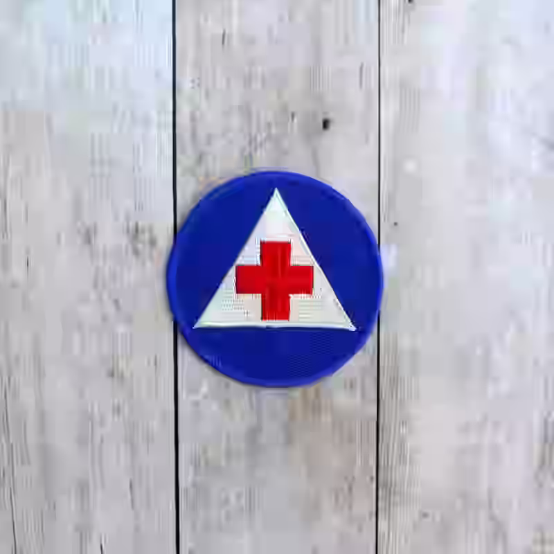 United States Women Army Corps Volunteer Nurses Aid Corps Badge - WWII-era US WAC Volunteer Nurses Aid Corps badge with white triangle and red cross on blue background.